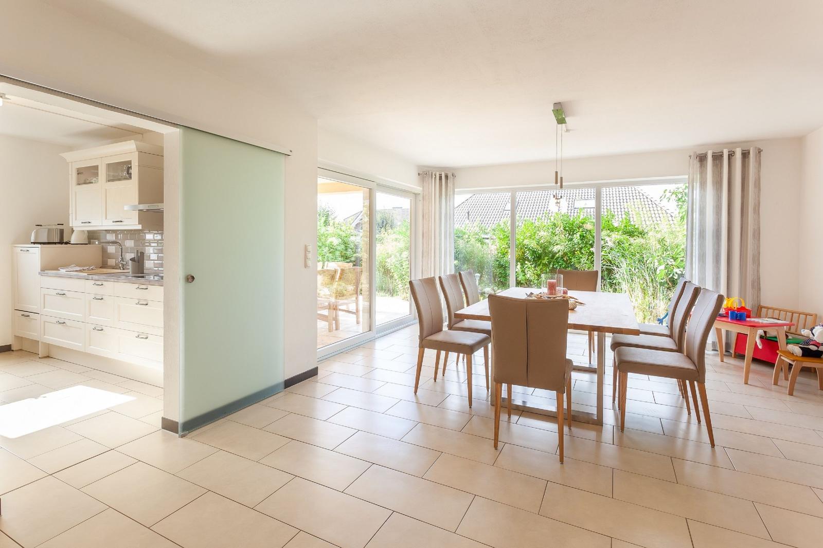 Essbereich mit Tisch und Stühlen, Küchenbereich und Terrasse mit Blick auf Garten.
