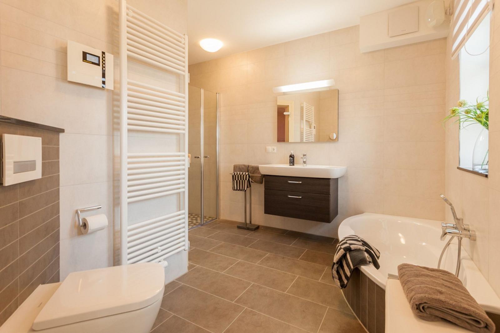 Badezimmer mit Badewanne, Dusche, Waschbecken und Heizkörper.