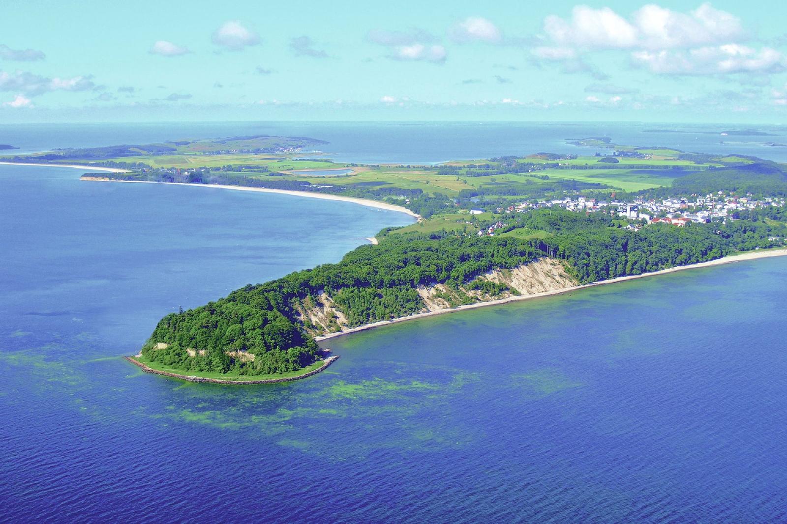 Aerial view of coastal landscape with green hills, beaches, and water.