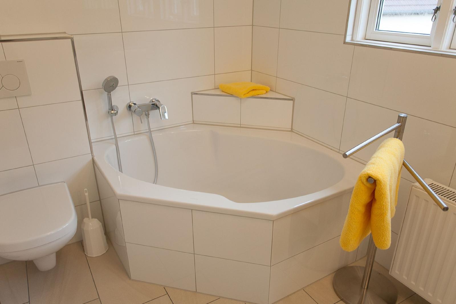 Bad mit Dusche, Badewanne und Toilette. Gelbe Handtücher sind vorhanden.