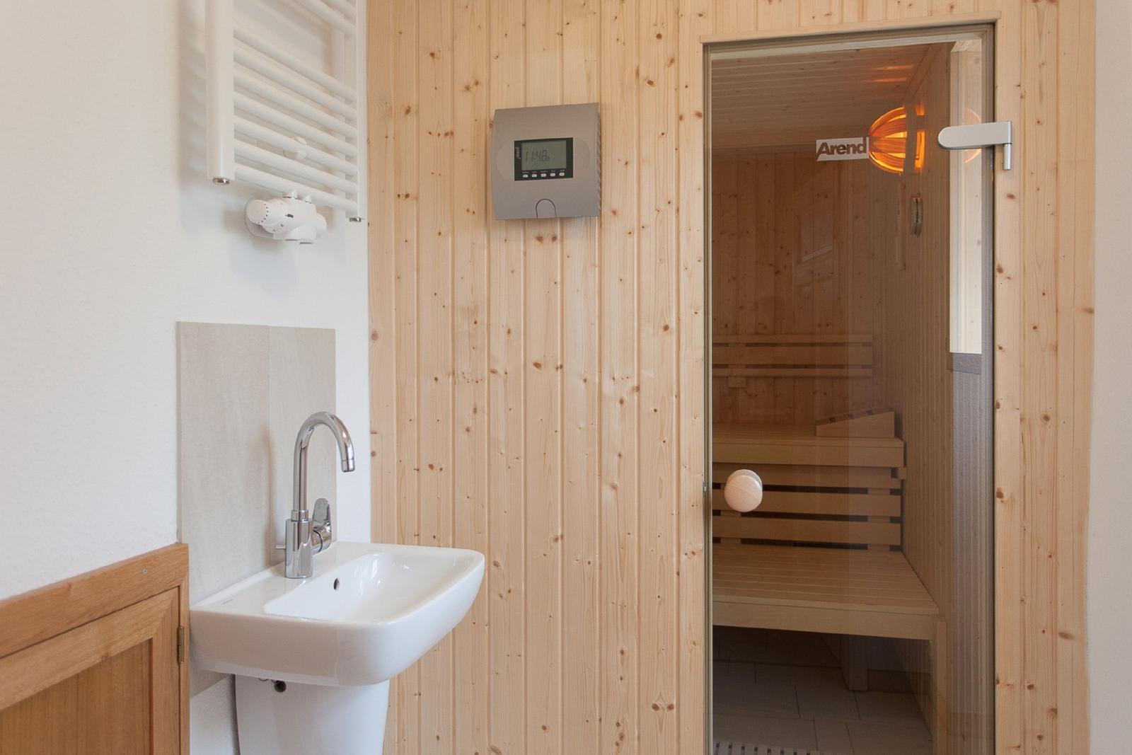 Dusche mit Sauna, Waschbecken und Heizung.