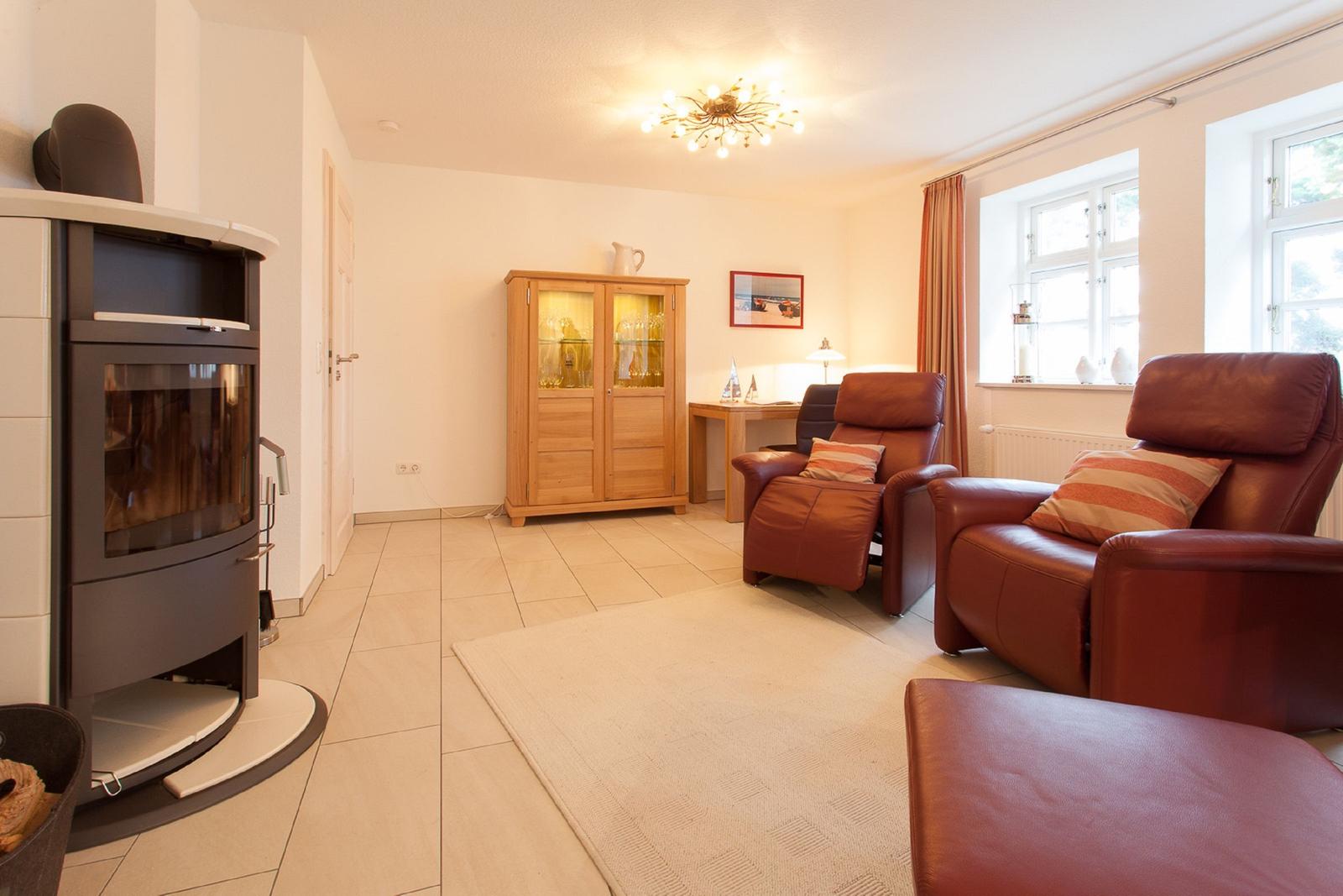 Wohnzimmer mit Kamin, zwei Ledersessel und Holzschrank.