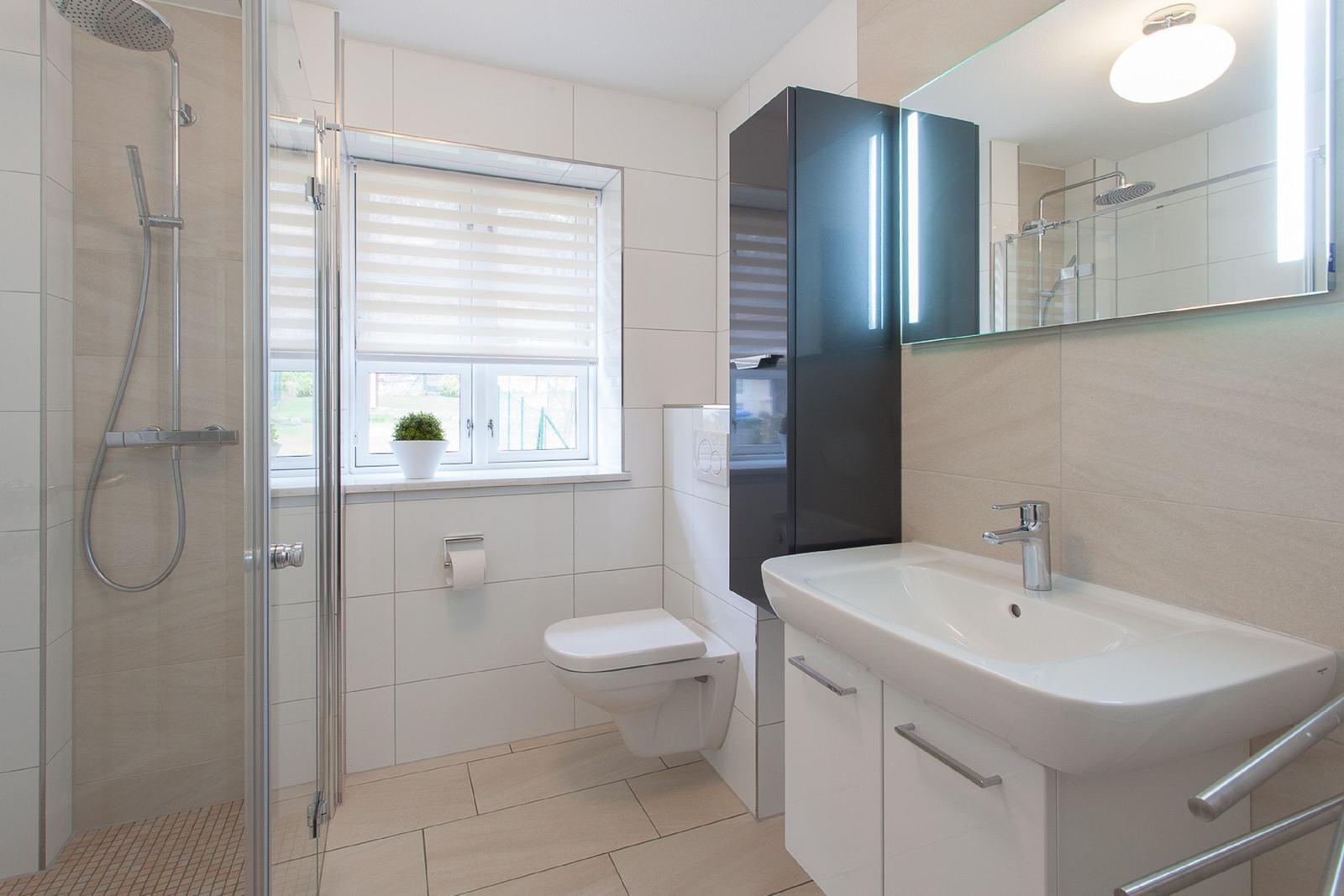 Badezimmer mit Dusche, WC und Waschbecken.