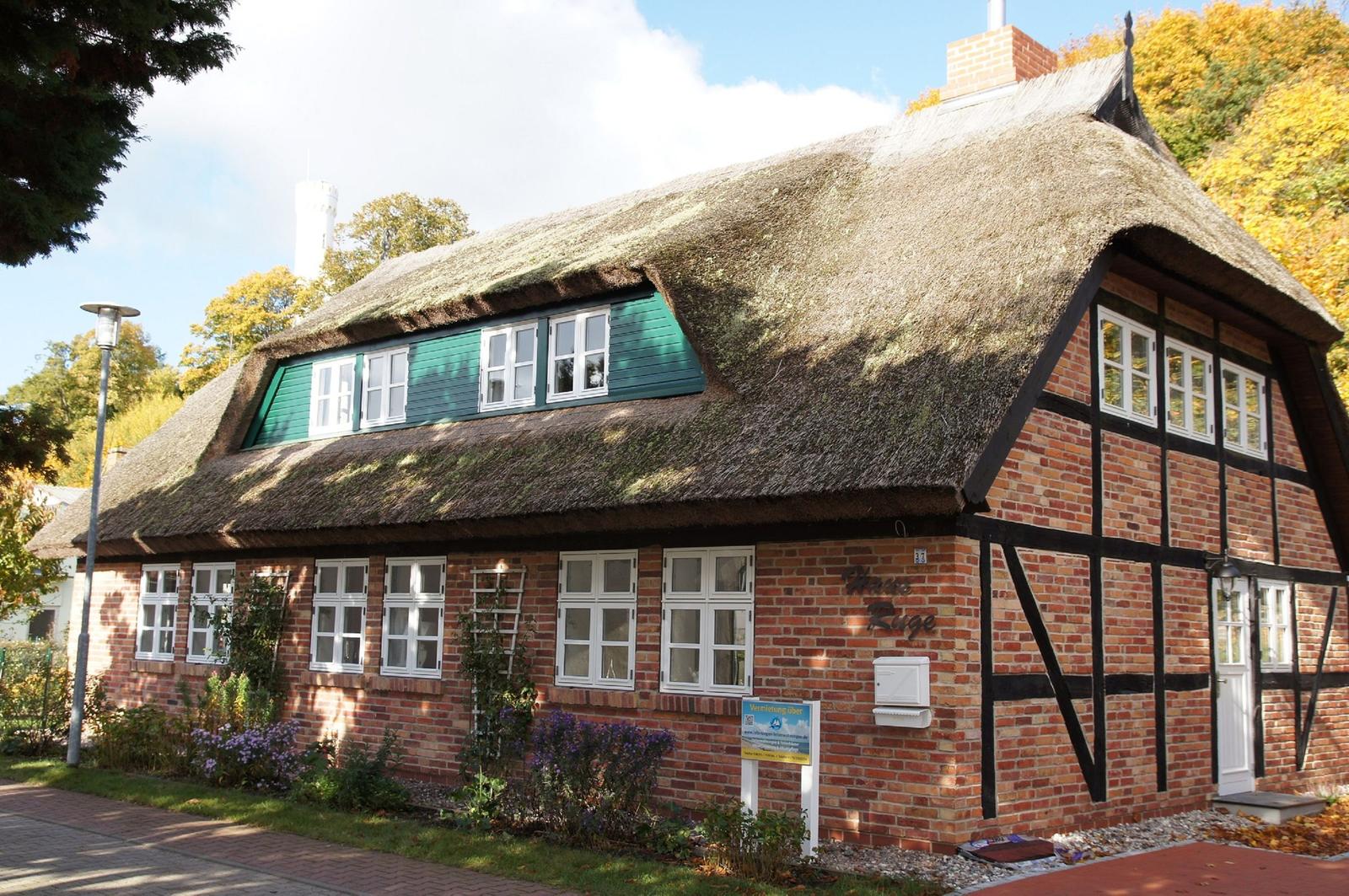 Traditionelles Haus mit Strohdach und Backsteinfassade im Herbst.
