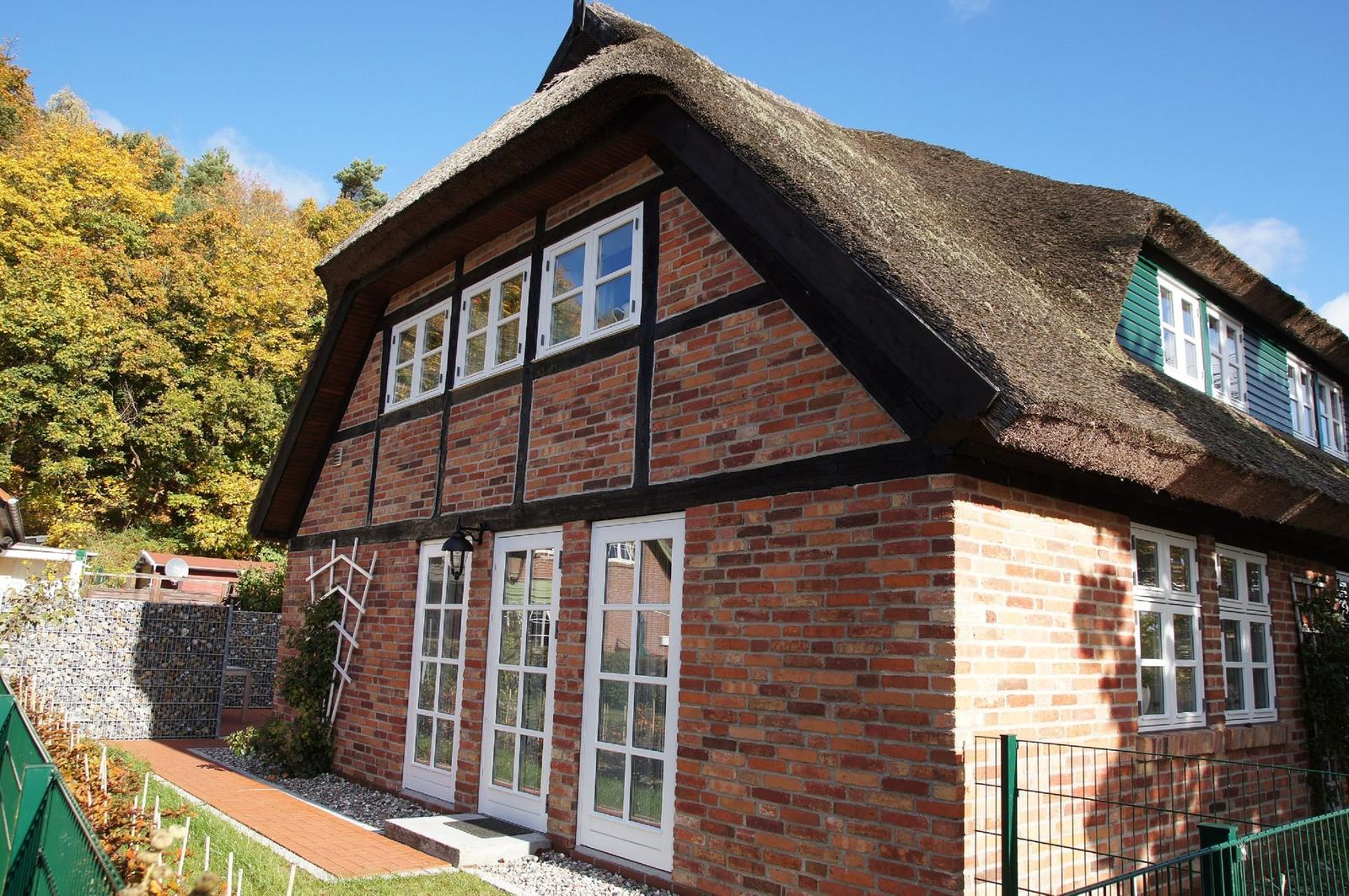 Rotes Backsteingebäude mit Strohdach und weißen Fenstern.