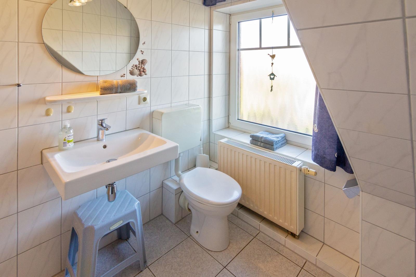 Badezimmer mit Waschbecken, Toilette und Fenster.