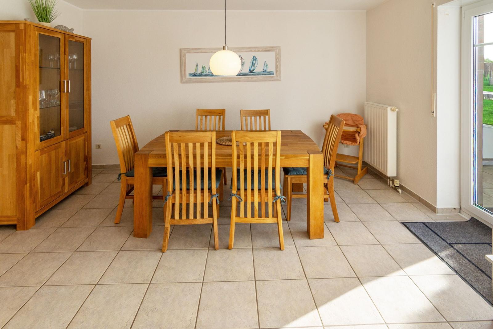 Esszimmer mit Holztisch, Stühlen und Sideboard. Wandbild mit Segelbooten.