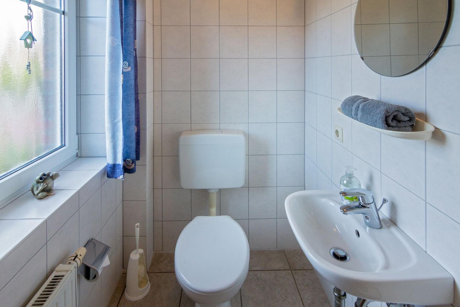 Badezimmer mit Toilette, Waschbecken und Fenster