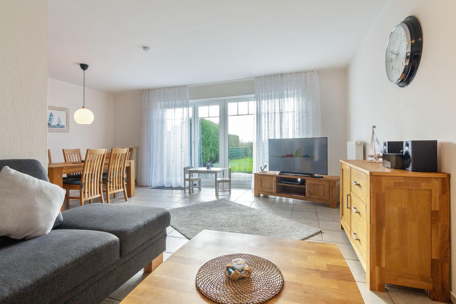 Wohn- und Essbereich mit TV, Sofa und Blick auf den Garten.