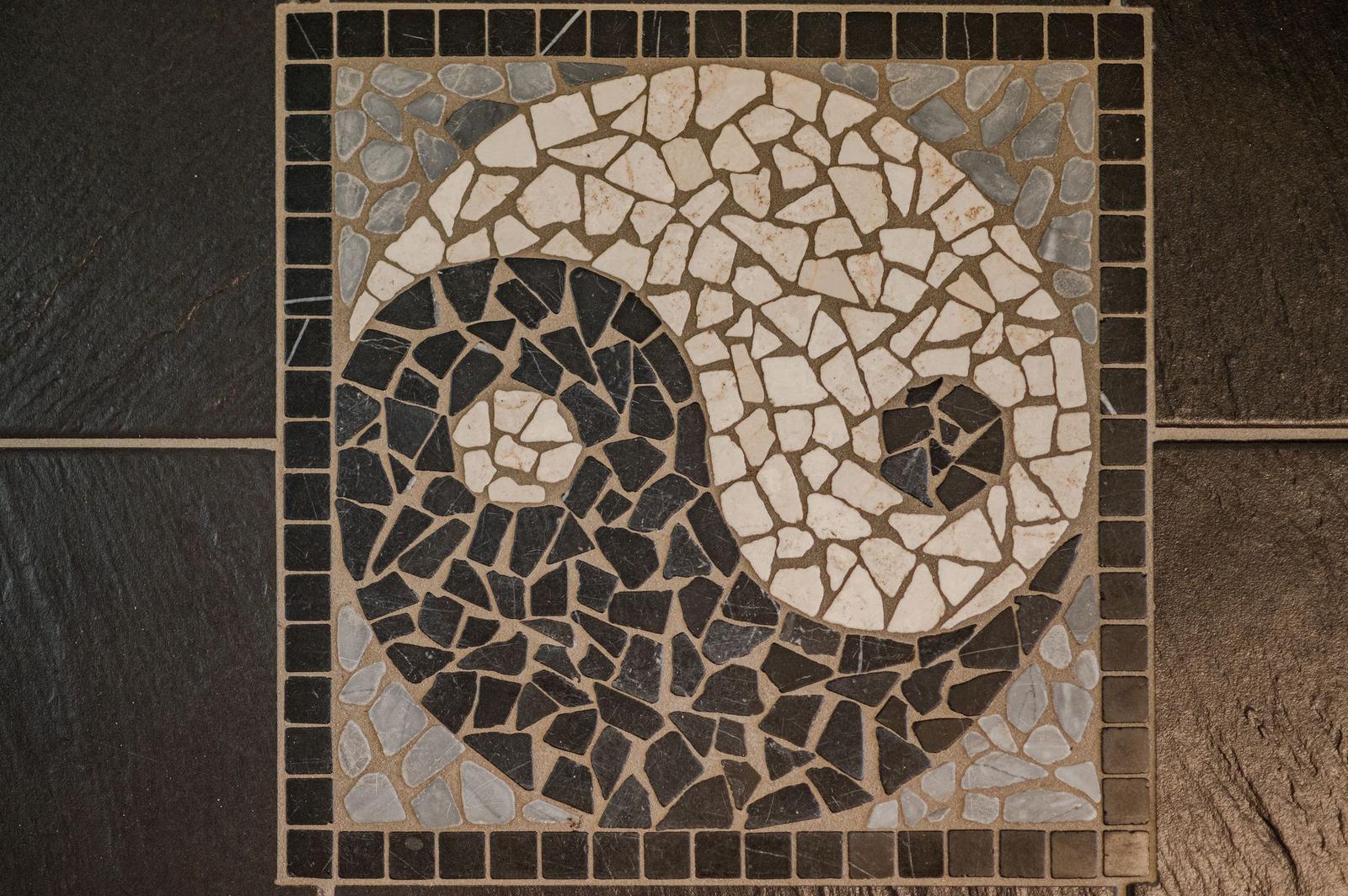Mosaikboden mit Spiralmuster aus schwarzen und weißen Steinen.