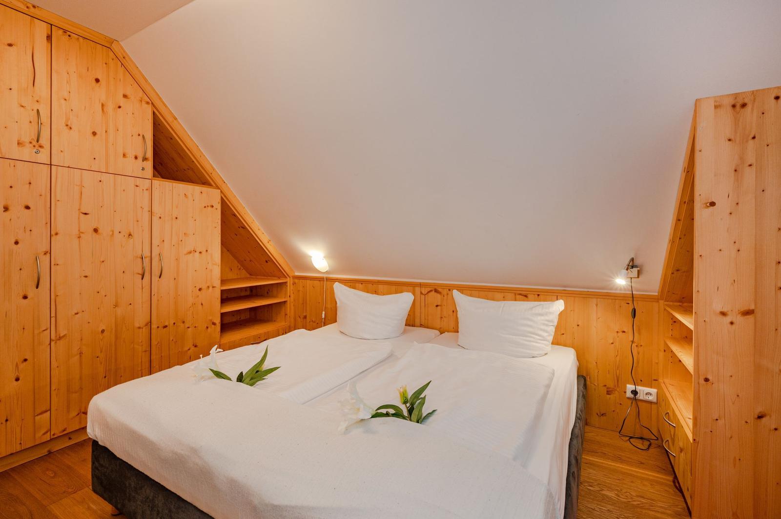 Schlafzimmer mit Doppelbett, Holzmöbel und Dachschrägen.
