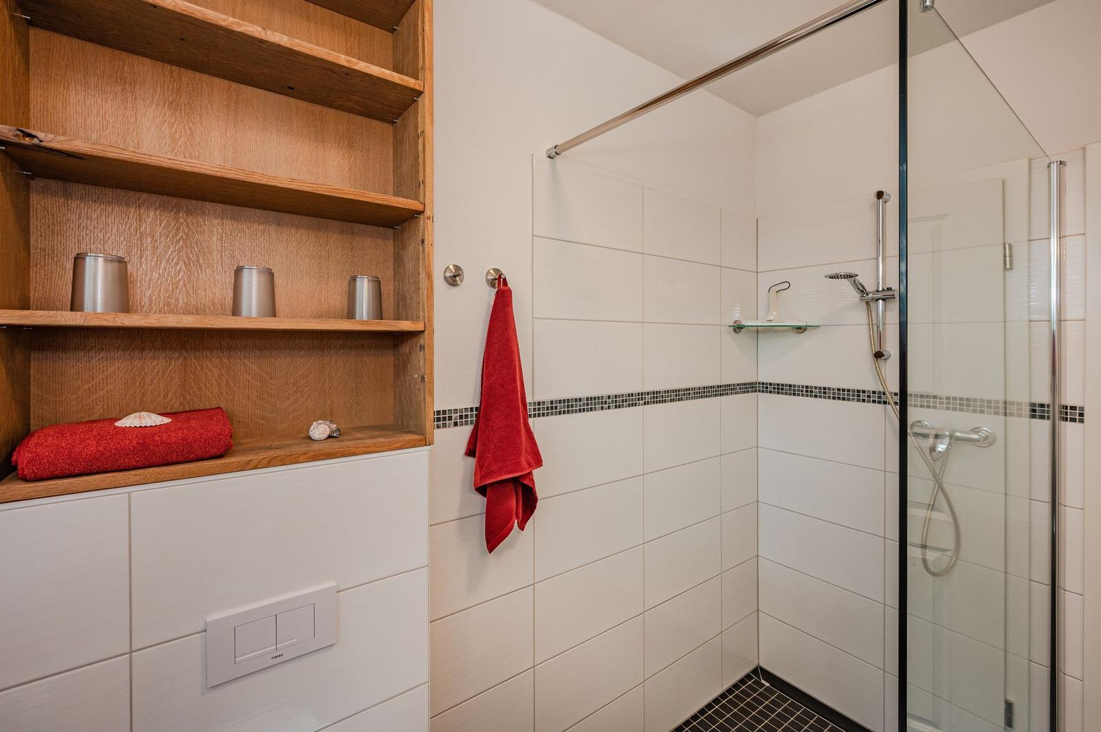 Dusche mit Glaswand, Holzregal und roter Handtuch