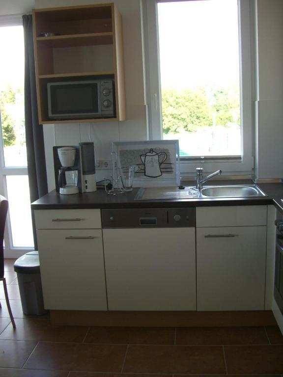 Küche mit Spüle, Mikrowelle und Kaffeemaschine unter Fenster