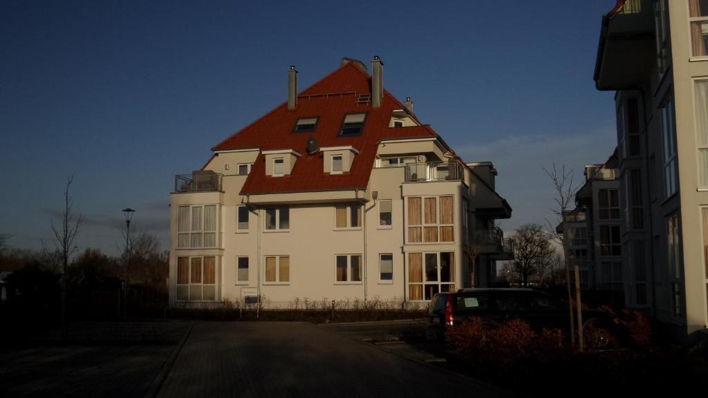 Wohnhaus mit rotem Dach und mehreren Fenstern im Abendlicht.