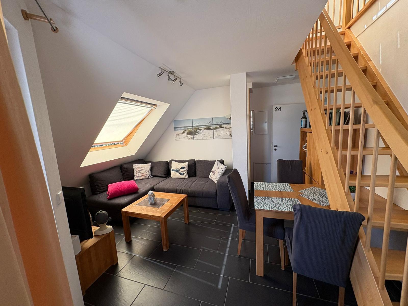 Wohn- und Essbereich mit Holztreppe und Dachschrägen.