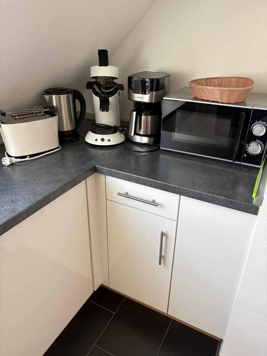 Küchenzeile mit Toaster, Kaffeemaschine, Mikrowelle und Korb.