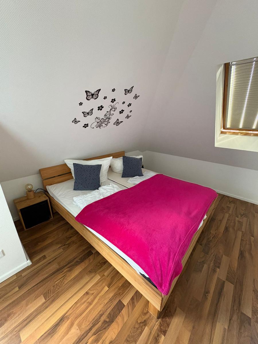 Schlafzimmer mit Holzboden, Bett und Wanddekoration.