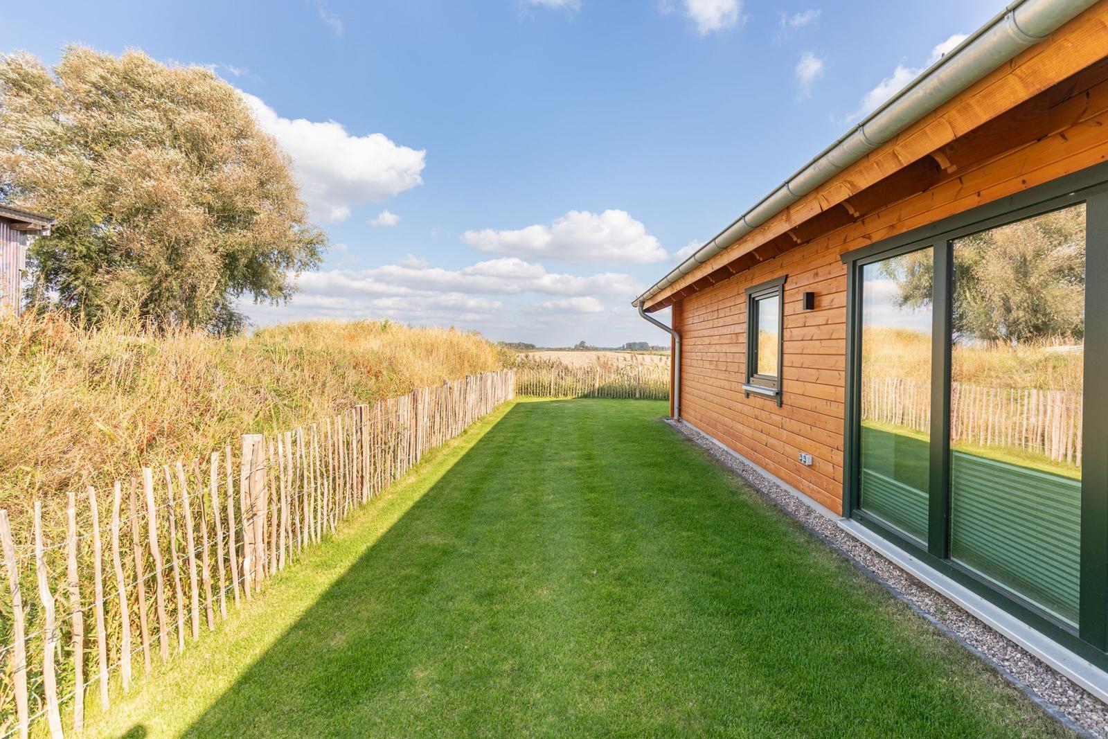 Holzhaus mit grünem Rasen und Zaun entlang des Grundstücks.