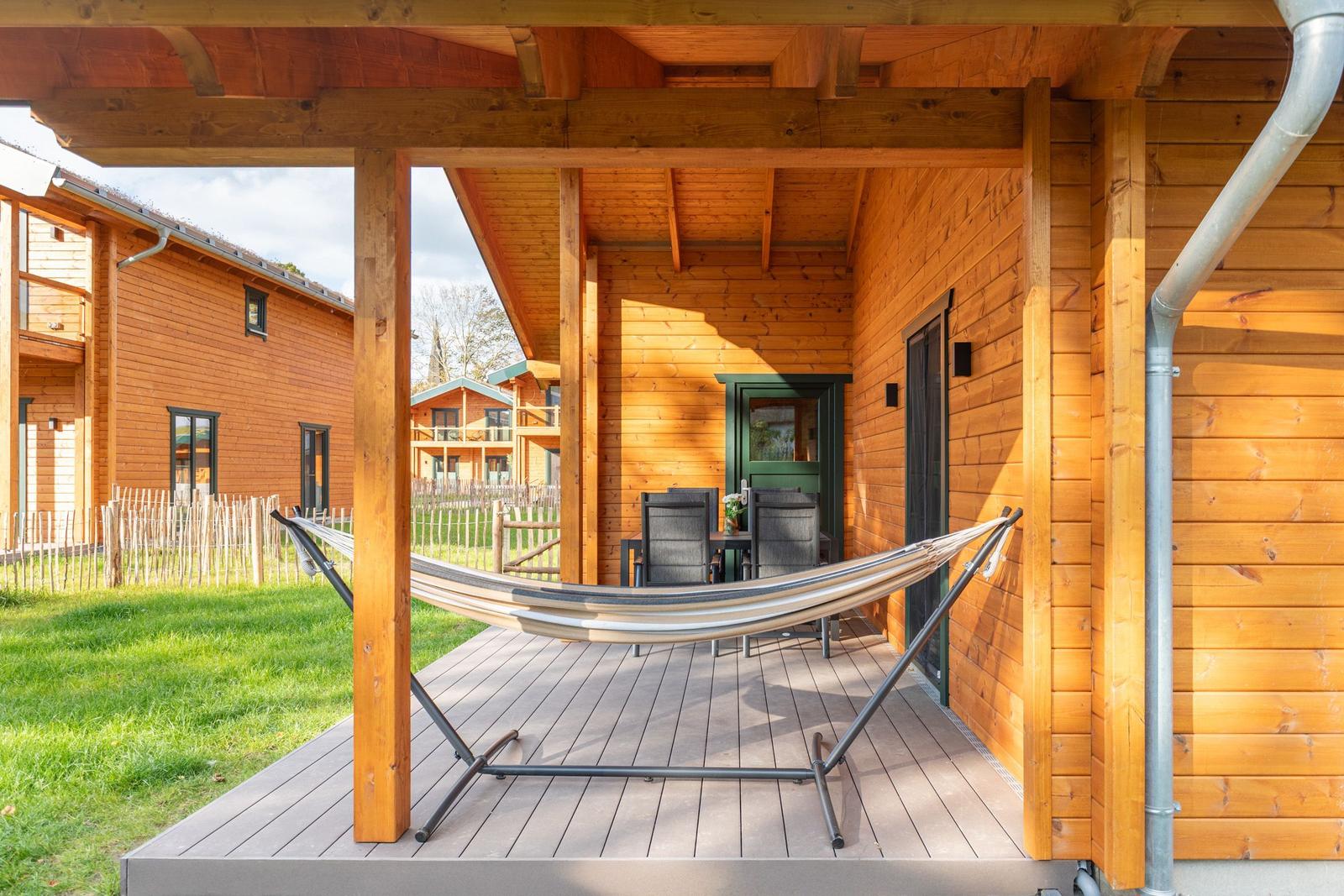 Terrasse mit Hängemattenaufstellplatz und Sitzgruppe unter Holzüberdachung.