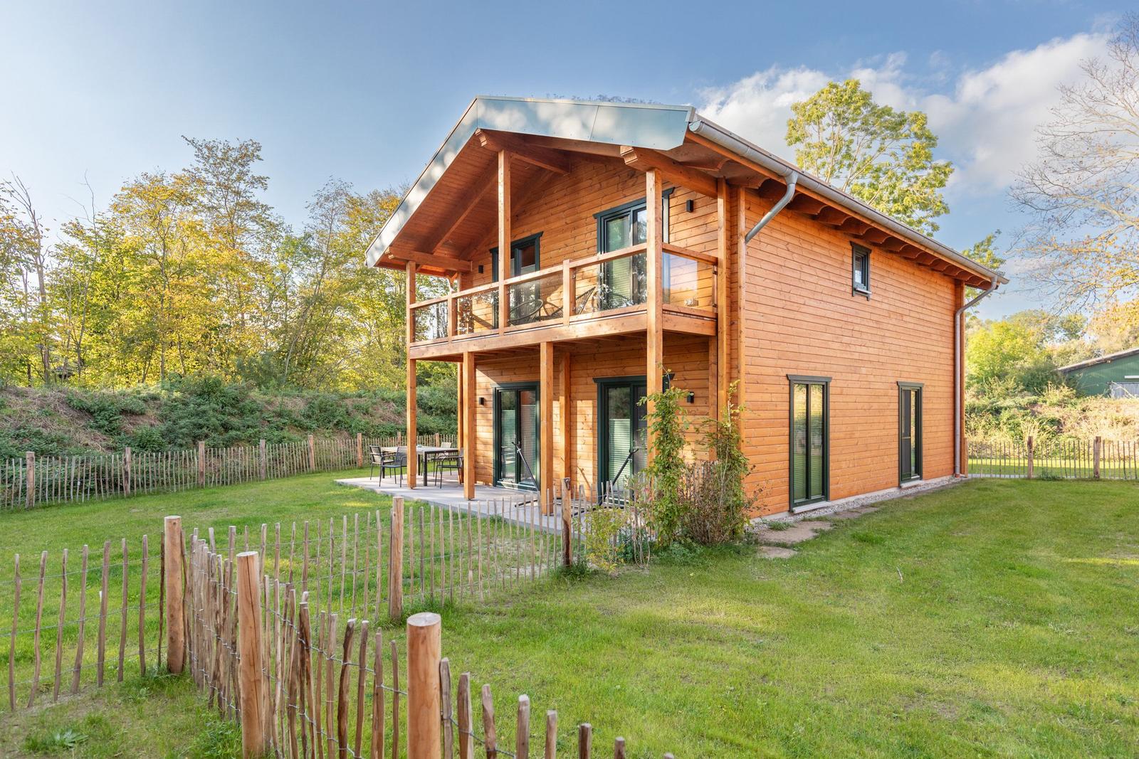 Holzhäuschen mit Balkon und Garten. Terrasse mit Tisch und Stühlen.
