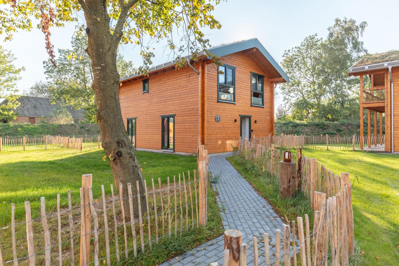 Holzhaus mit Garten und Steintreppe. Holzgeviert und grüner Rasen.