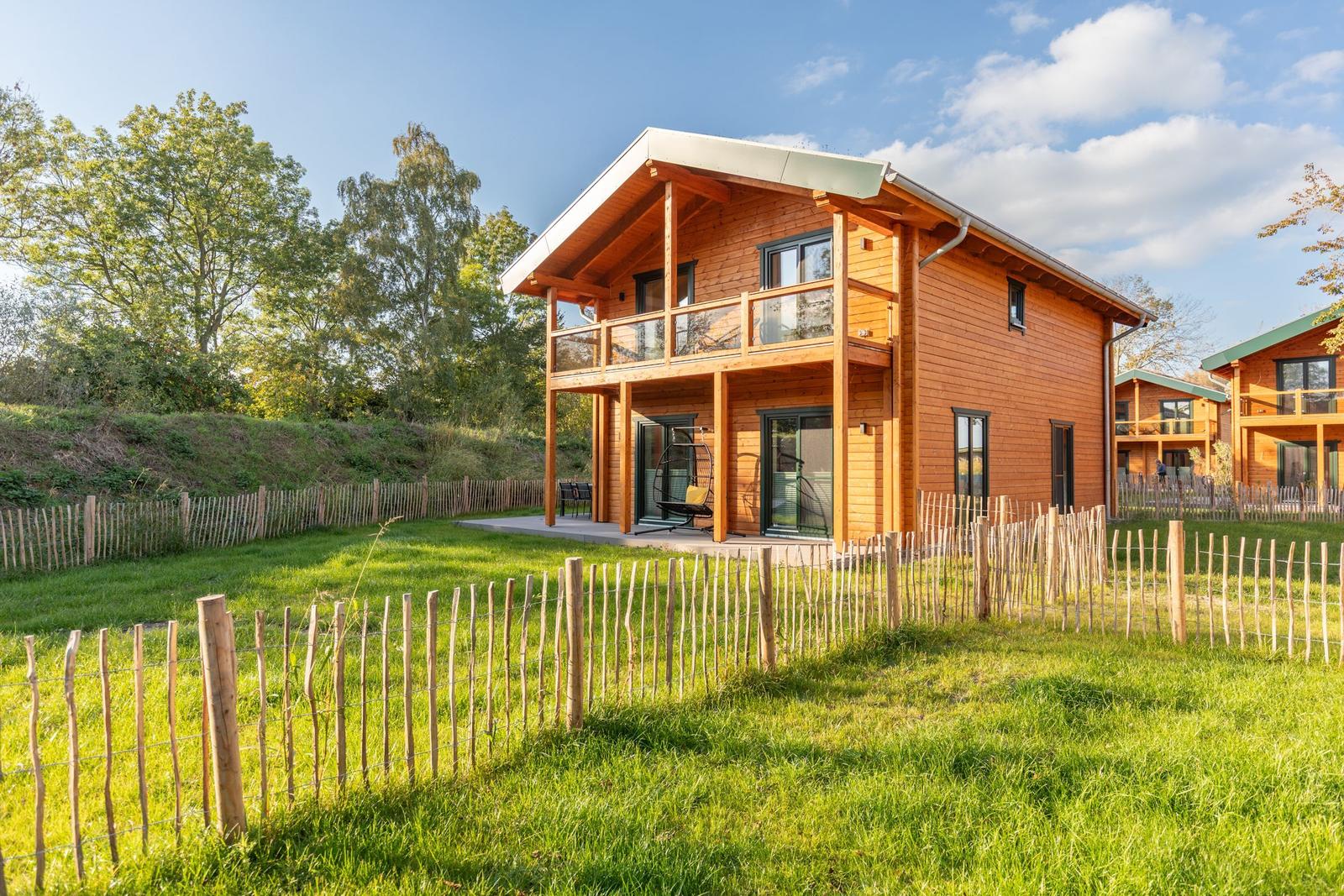 Holzhaus mit Balkon und Gartenzaun im Grünen