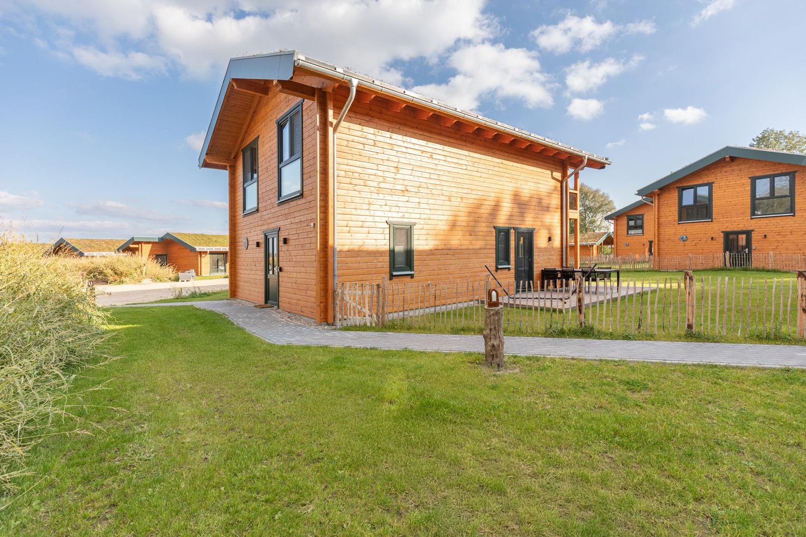 Holzhaus mit Terrasse und Garten. Mehrere Häuser im Hintergrund.