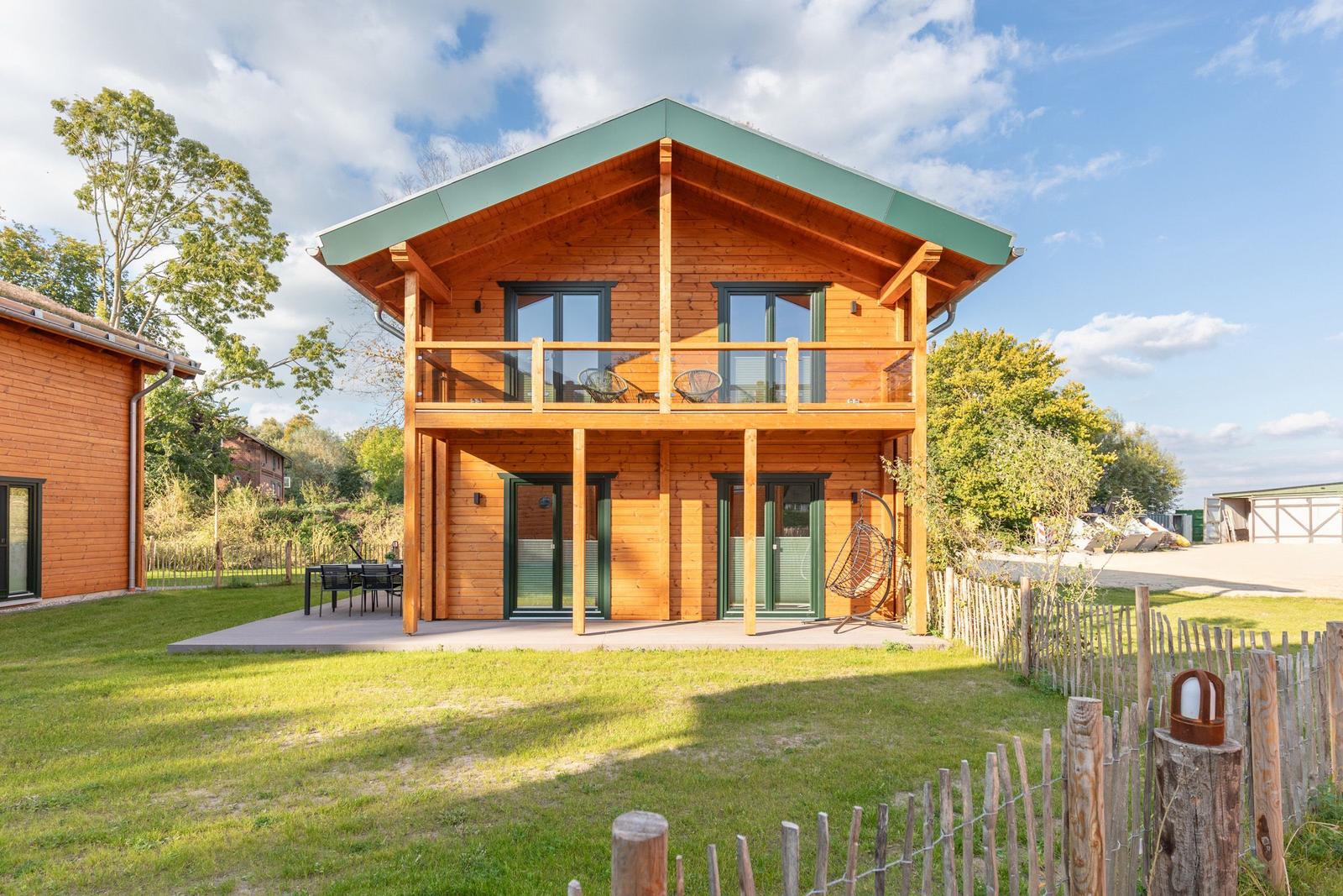 Holzhäuschen mit Balkon, Terrasse und Garten. Grün-dach und Holzwände.