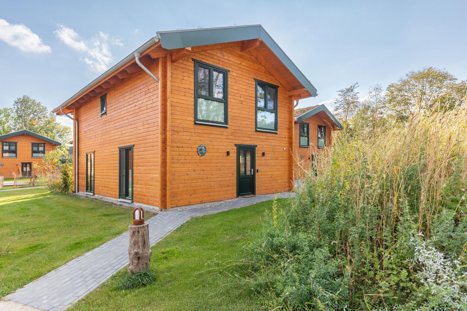 Holzhaus mit grüner Umgebung und gepflastertem Weg.