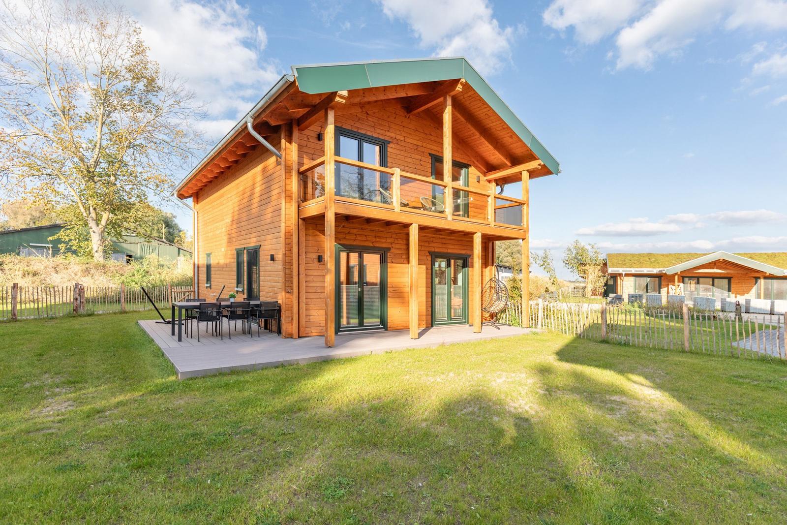 Holzhaus mit Balkon und Terrasse im Grünen.