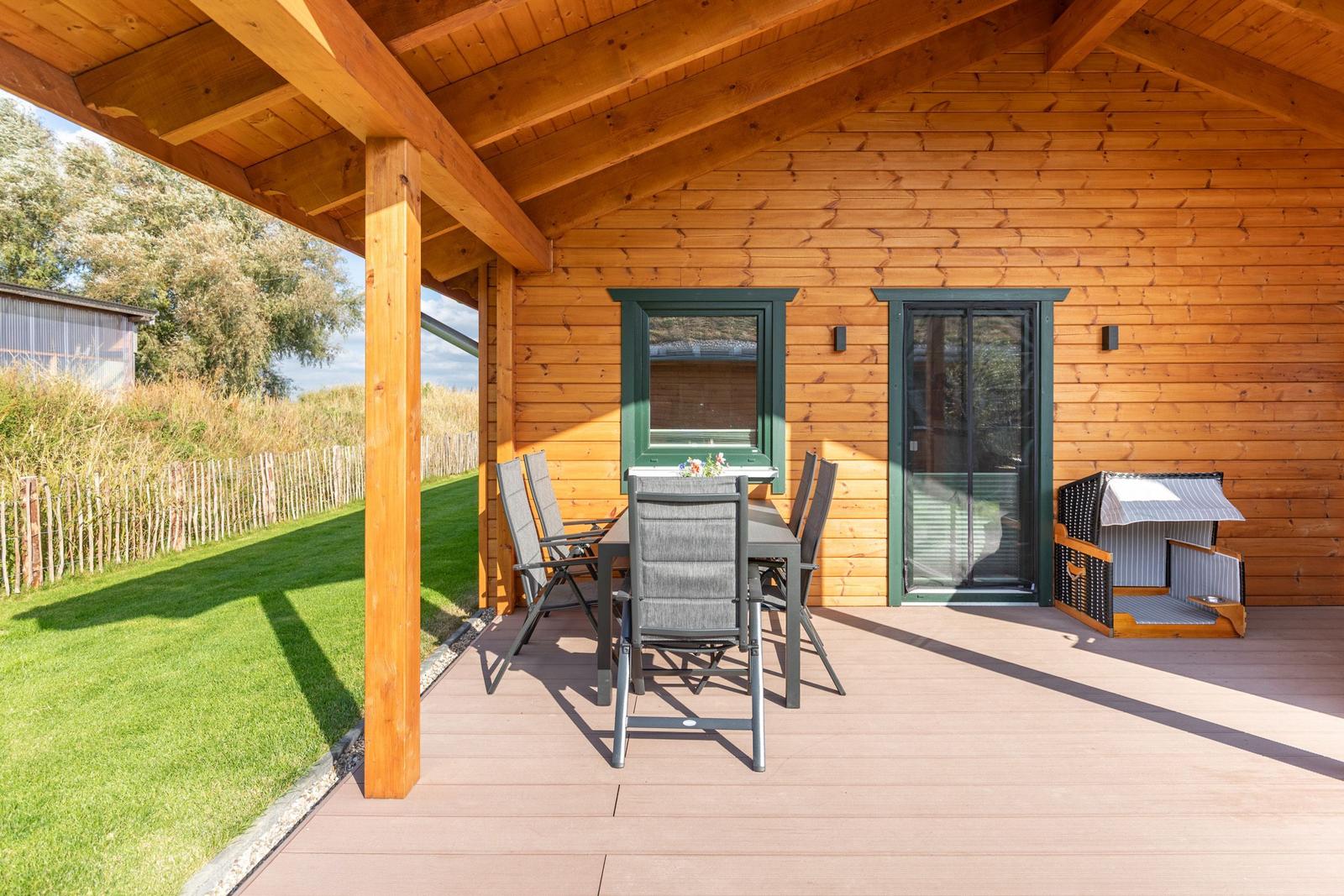 Terrasse mit Tisch, Stühlen und Hundebox an Holzhaus.