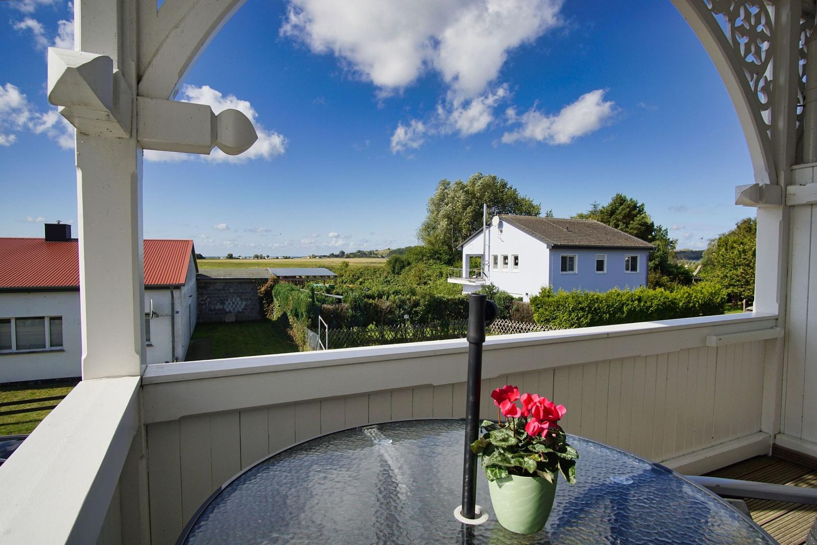 Terrasse mit Tisch und Blume, Blick auf Haus und Landschaft.
