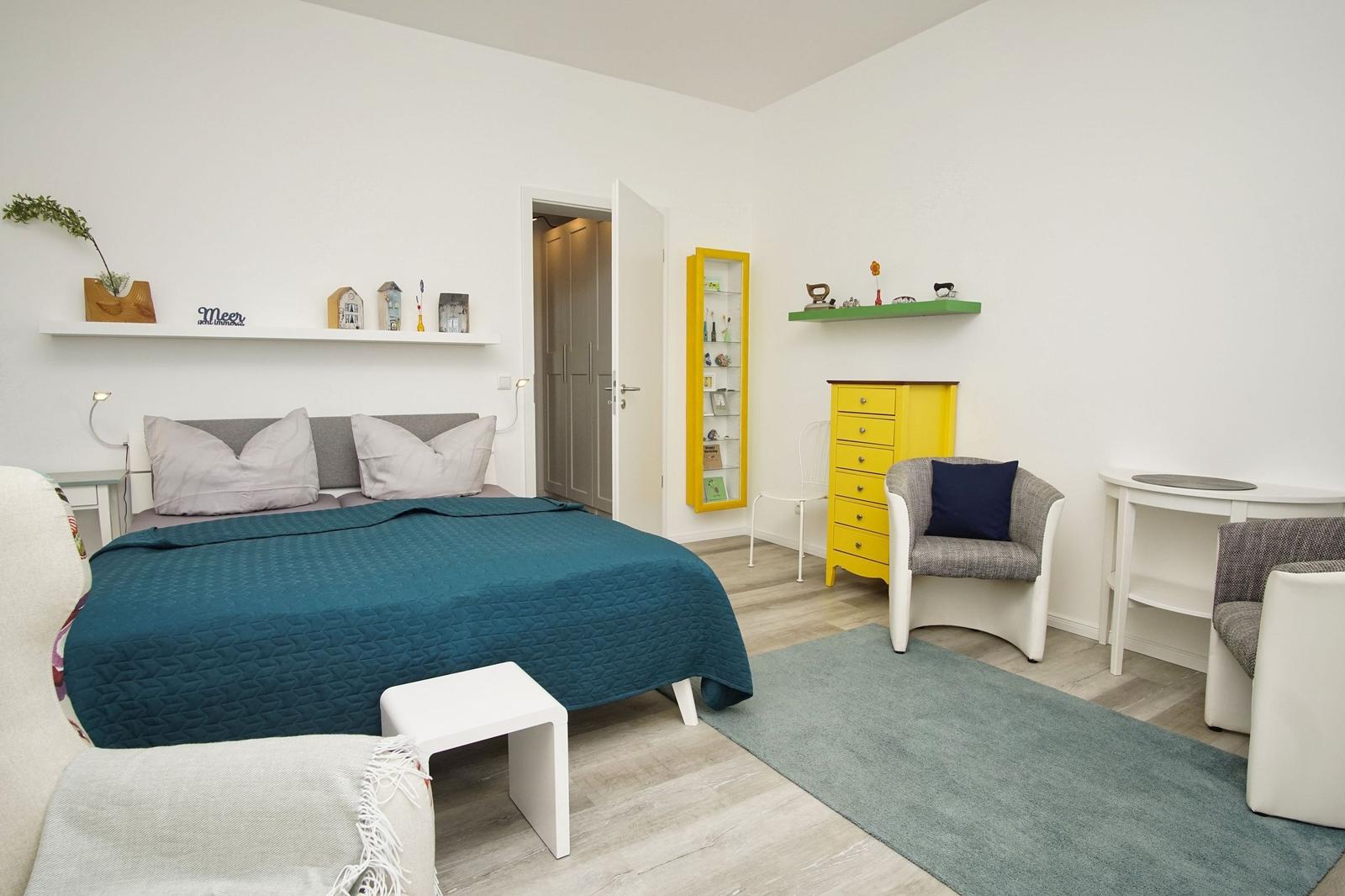 Schlafzimmer mit Bett, Schrank und Sitzgelegenheiten.