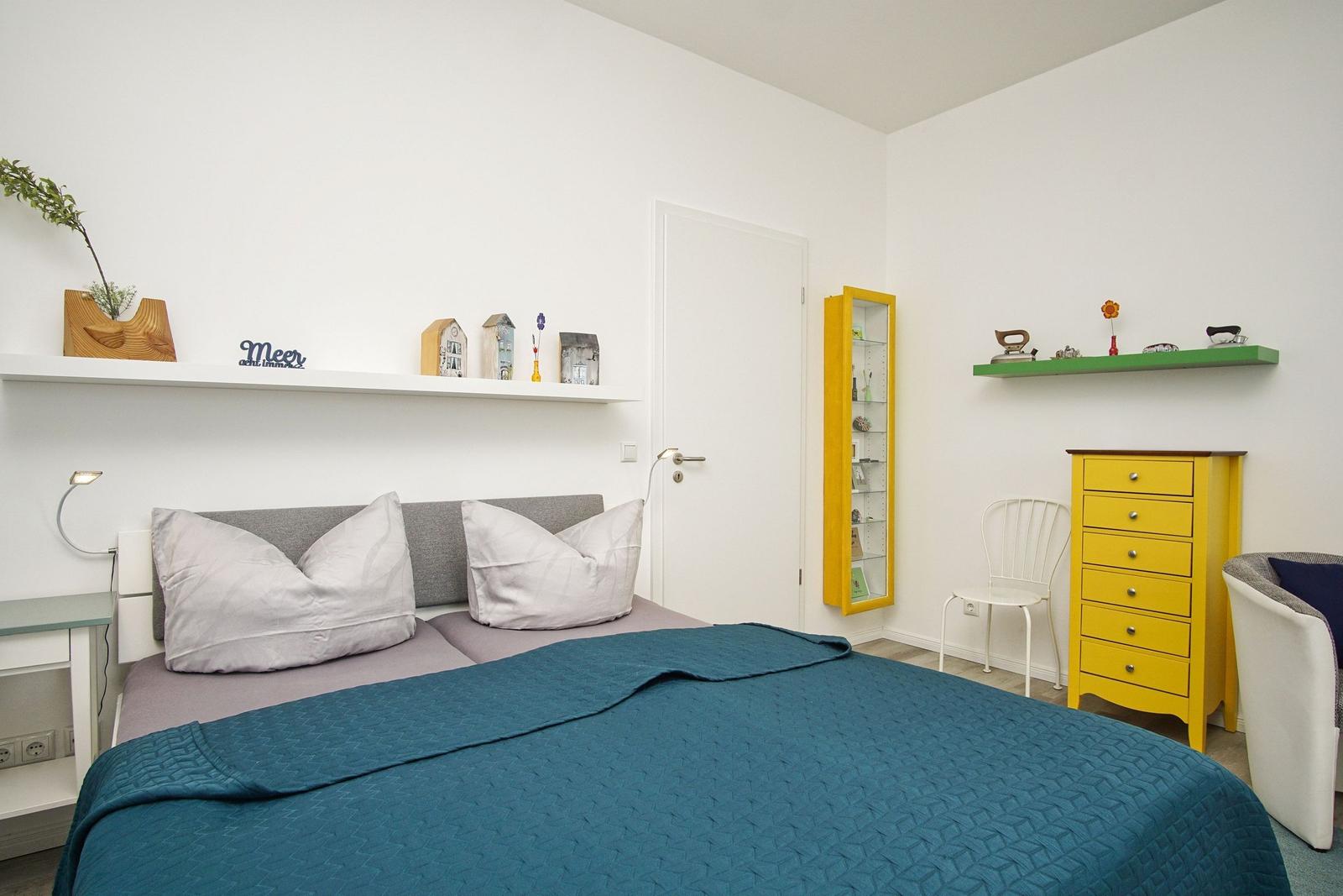 Schlafzimmer mit Bett, Schrank und Regal. Wandregale mit Dekoration.