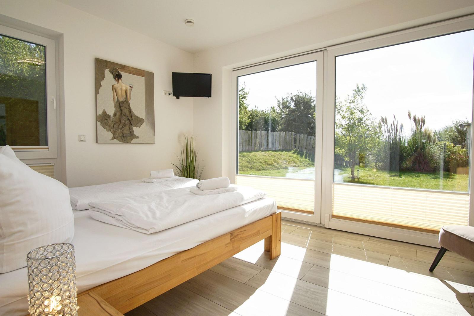 Schlafzimmer mit Doppelbett, TV und Blick auf Garten.