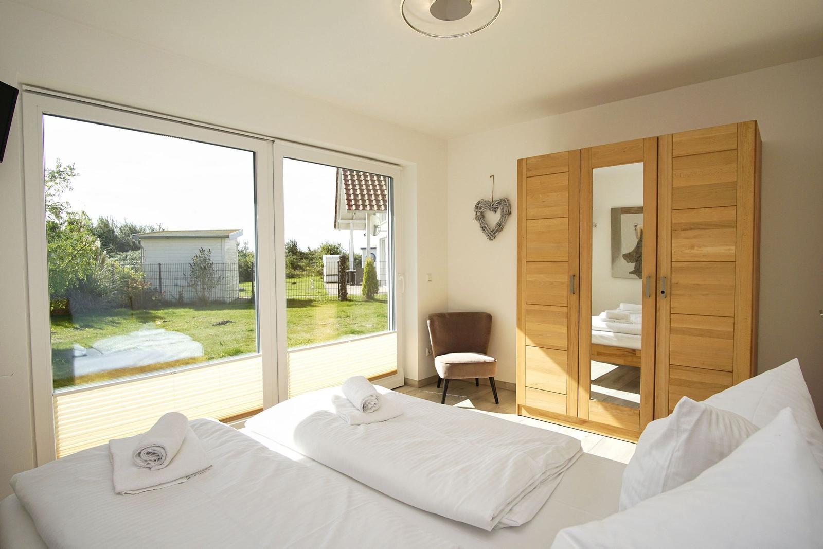 Zimmer mit Doppelbett, Holzschrank und Blick auf Garten