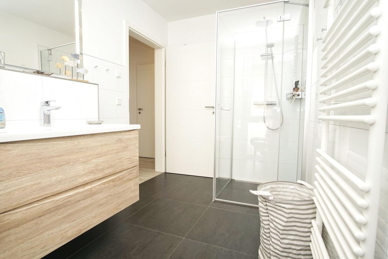 Badezimmer mit Dusche, Waschtisch und Heizkörper.