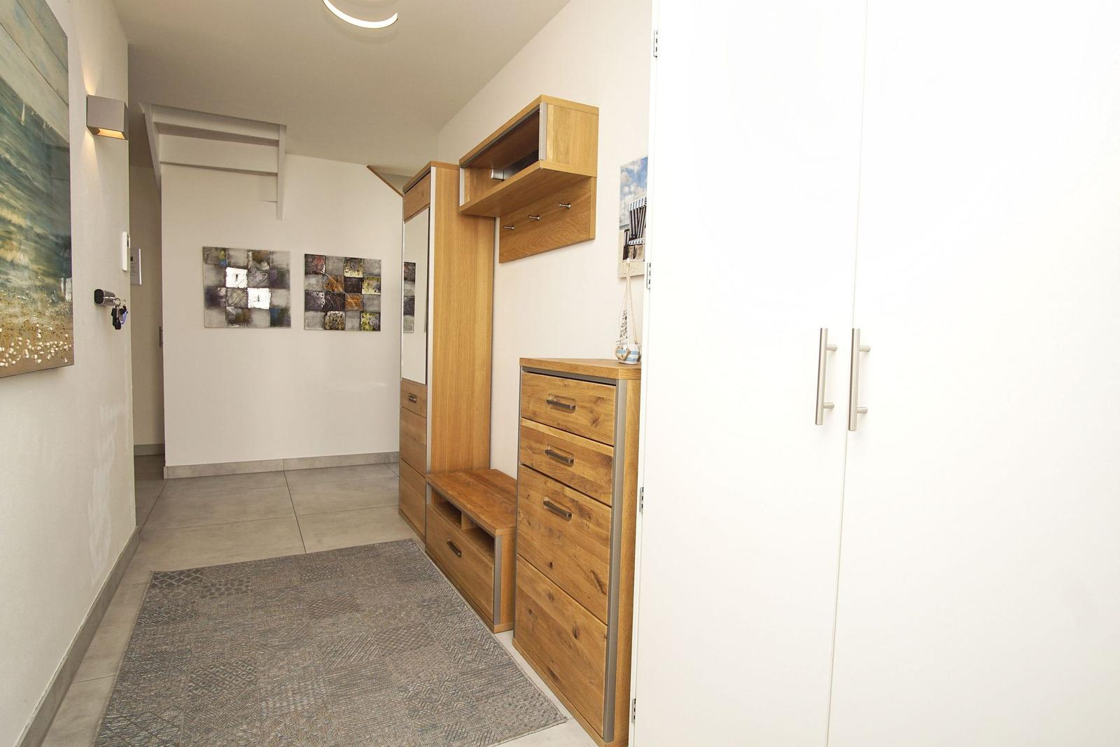 Eingangsbereich mit Holzmöbeln, Teppich und Wandbildern.