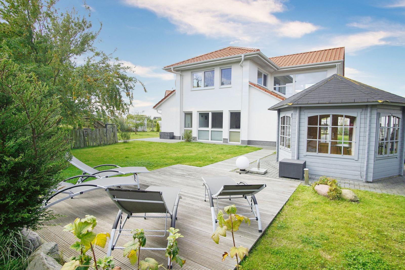 Wohnhaus mit Terrasse, Liegen und Garten. Nebenhaus mit Glasfront.