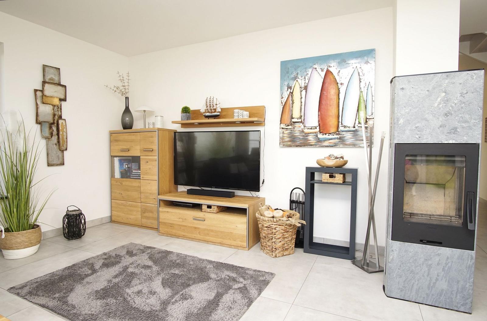 Wohnzimmer mit Fernseher, Kamin und Wandbild mit Segelbooten.