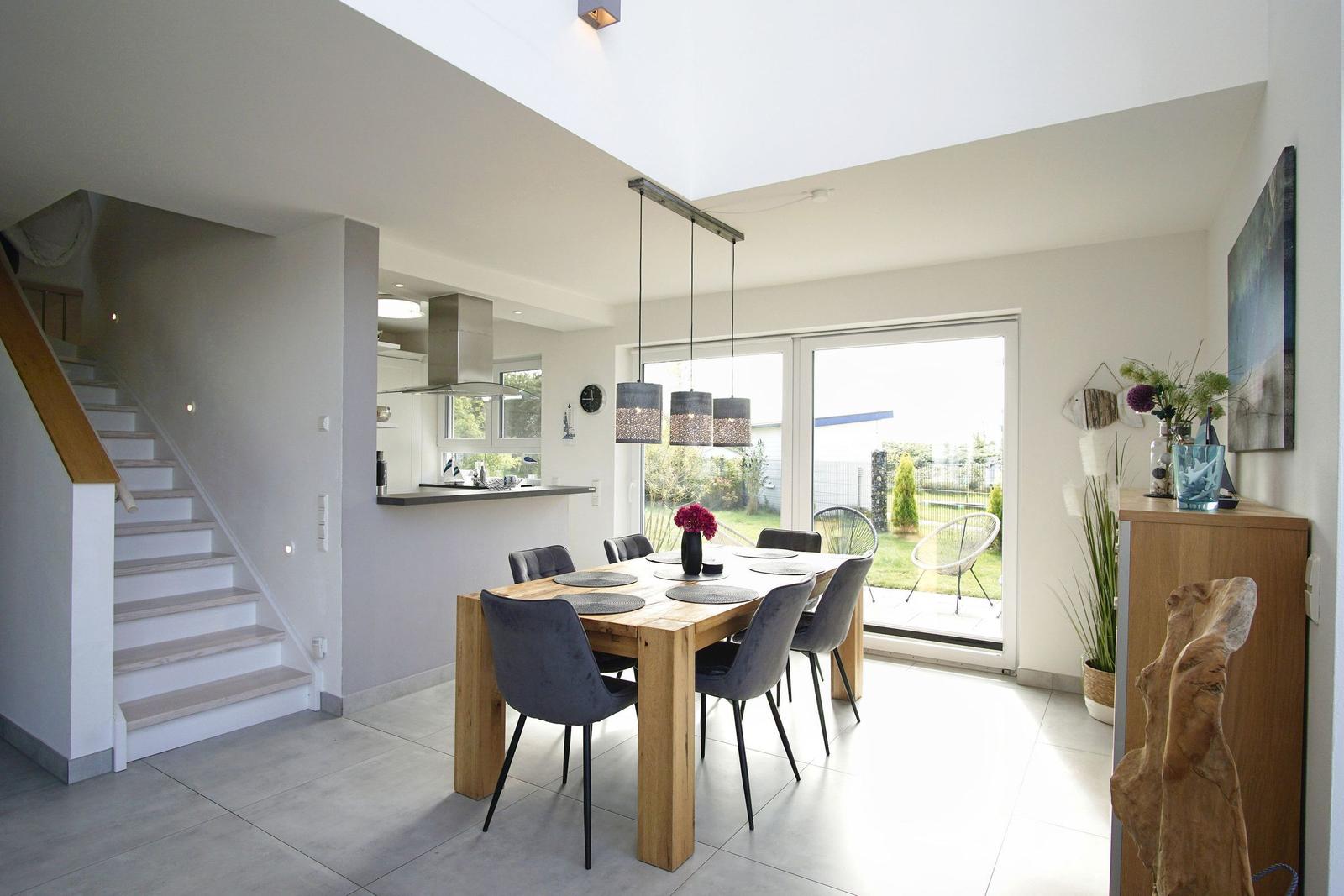 Esszimmer mit Holztisch, Stühlen und Blick auf die Terrasse.