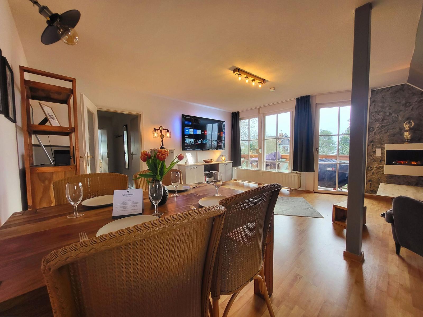 Essbereich mit Tisch und Stühlen, Fernseher und Kamin im Hintergrund.