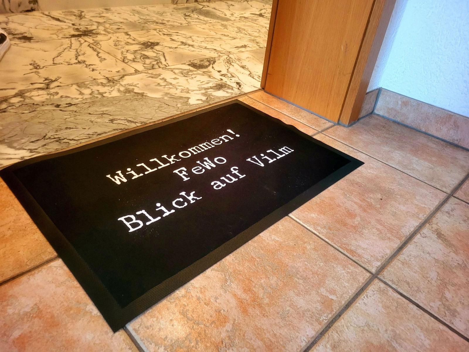 Willkommen-Matte vor Tür mit Blick auf Vilm