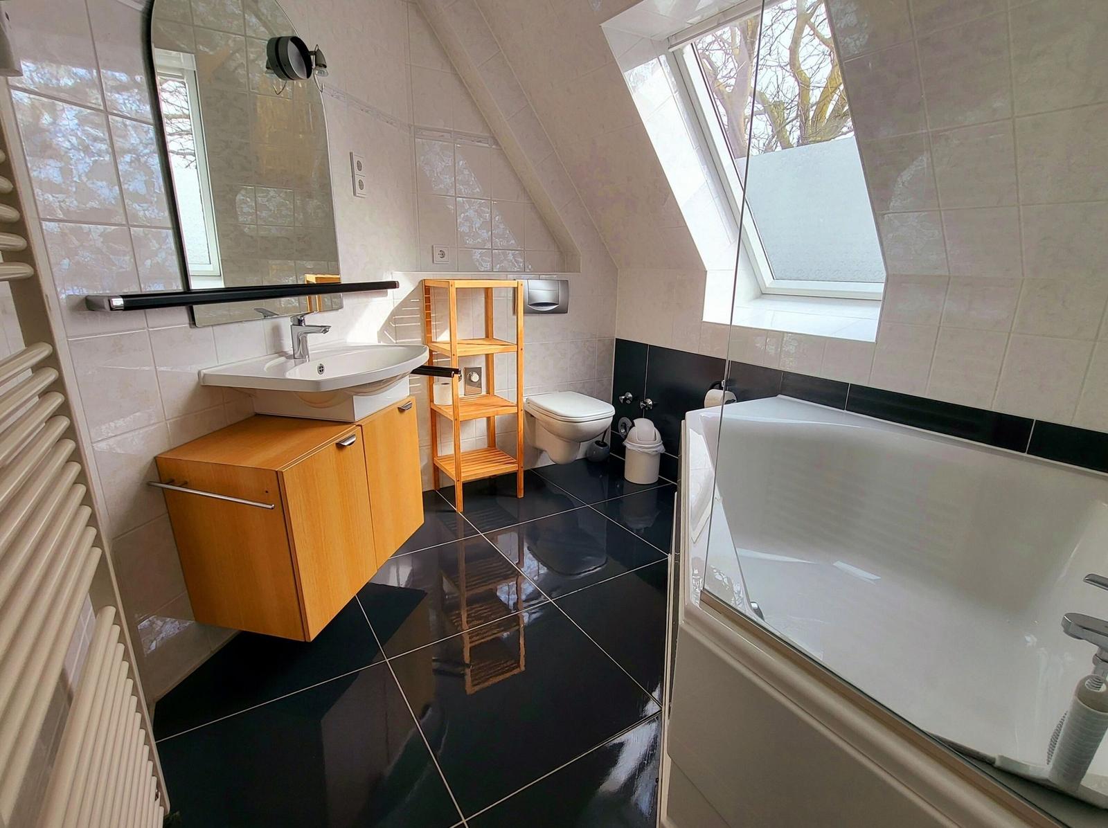 Badezimmer mit Dusche, Badewanne, Waschbecken und Toilette unter Dachschrägen.