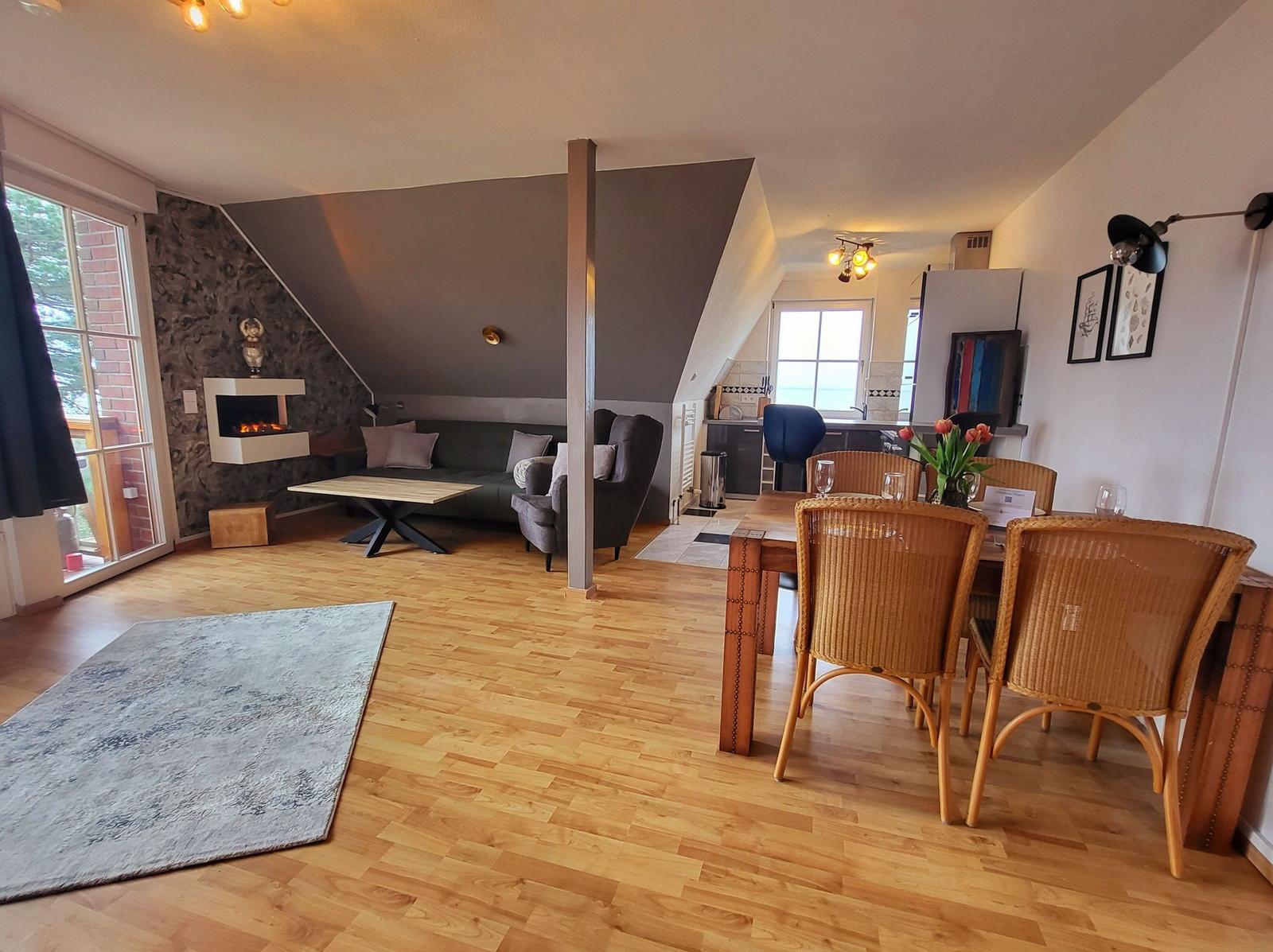 Wohn- und Essbereich mit Kamin, Holzboden und Sitzgelegenheiten.