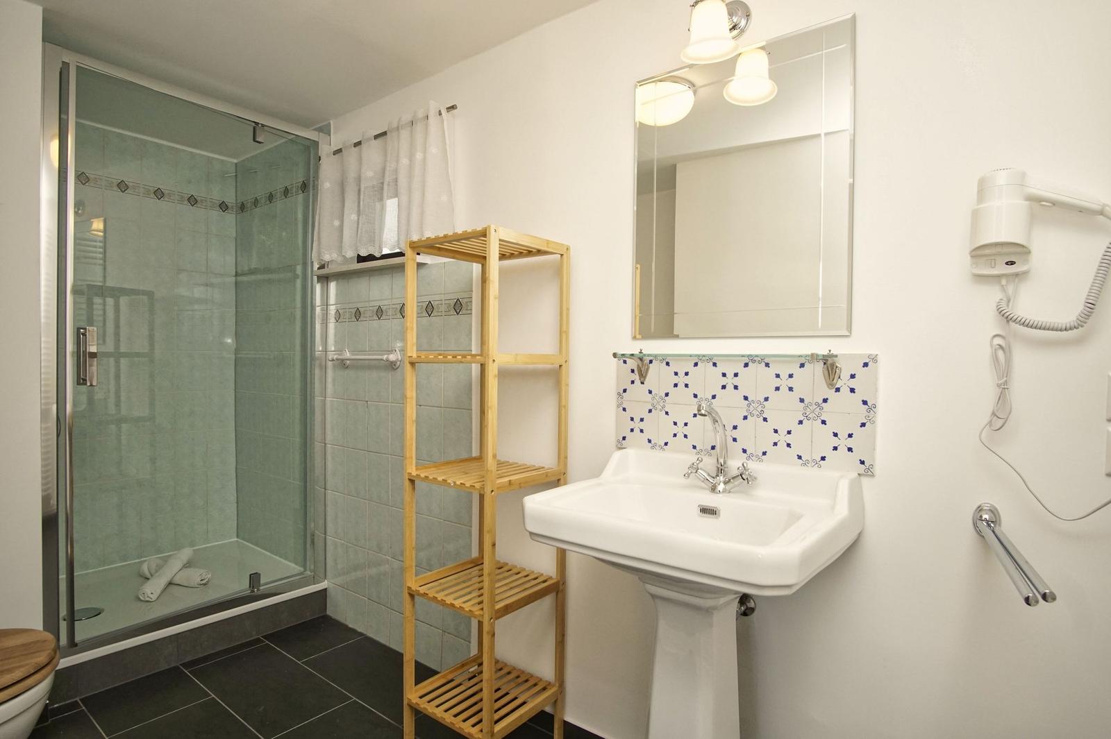 Badezimmer mit Dusche, Waschbecken und Handtuchhalter.