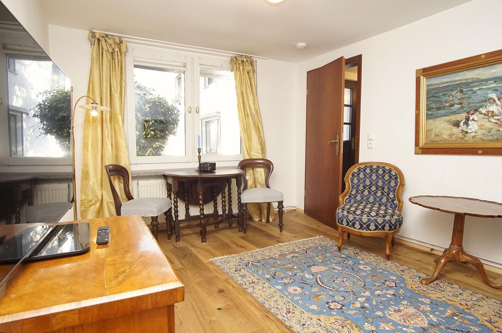 Ein Raum mit Holzboden, einem blauen Teppich und einem Gemälde an der Wand.