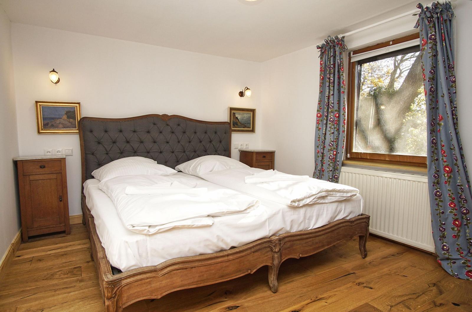 Ein Schlafzimmer mit einem großen Bett, Holzboden und einem Fenster mit Vorhängen.