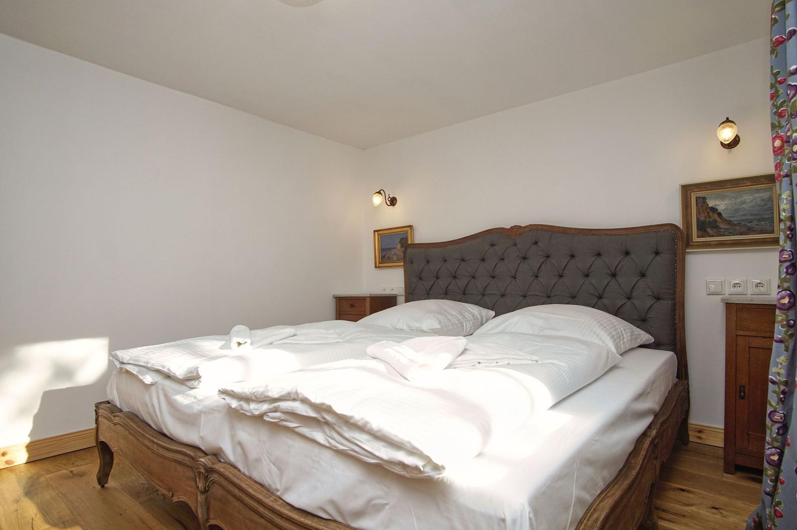 Ein Schlafzimmer mit einem Bett, zwei Nachttischen und Bildern an den Wänden.