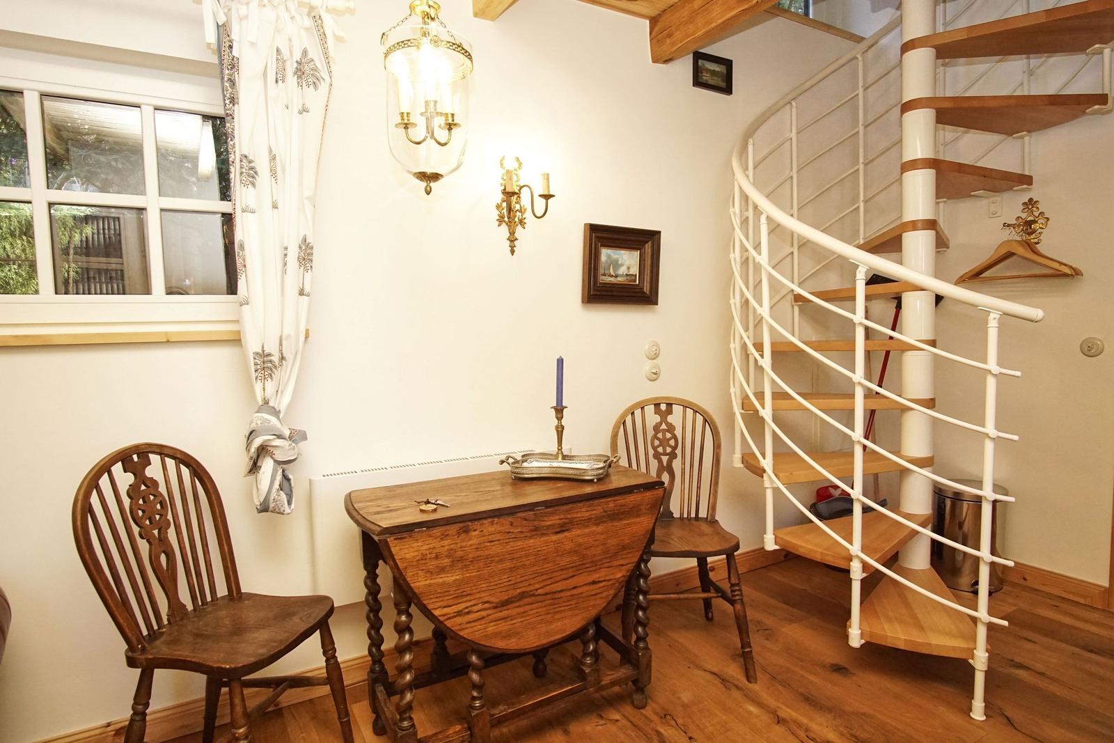 Eckzimmer mit Holztisch, zwei Stühlen und Wendeltreppe.